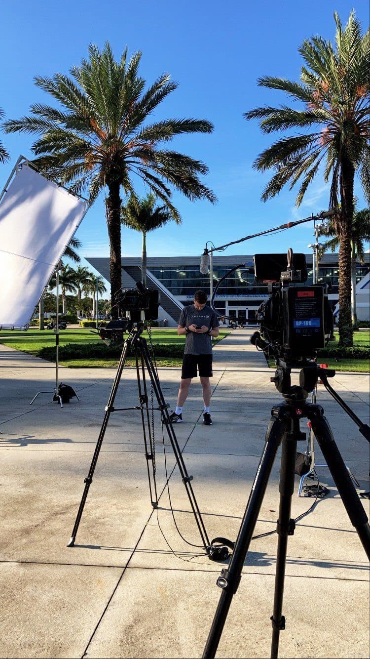 Cinema camera on a tripod under palm trees