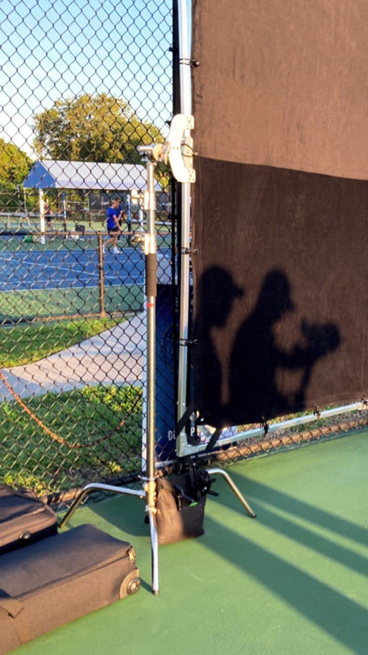 Shadow of a camera operator on a court fence